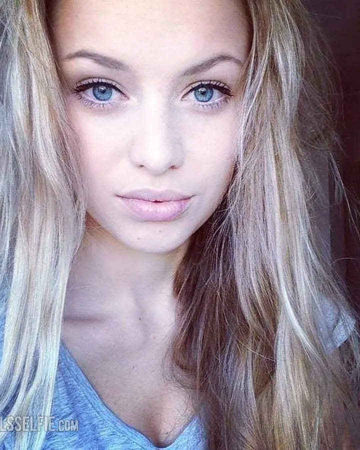 Femme blonde en maillot rouge prenant un selfie dans un miroir.