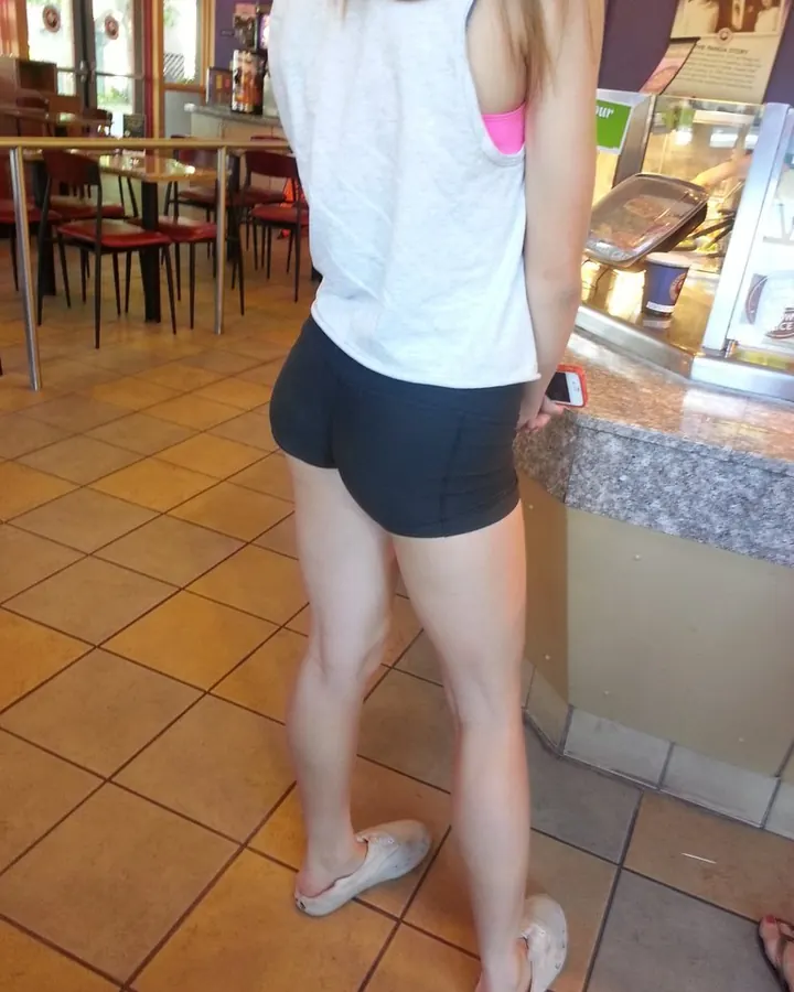 Jeune femme de dos en short noir et débardeur blanc dans un fast-food