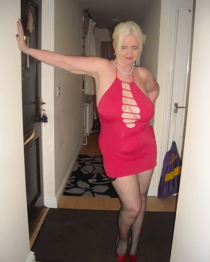 Femme blonde en robe rose courte à découpes, collants résille, talons rouges