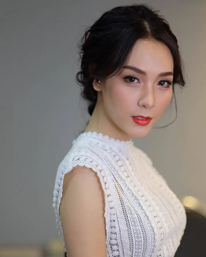 Femme asiatique au maquillage soigné, chemisier blanc ajouré, regard intense