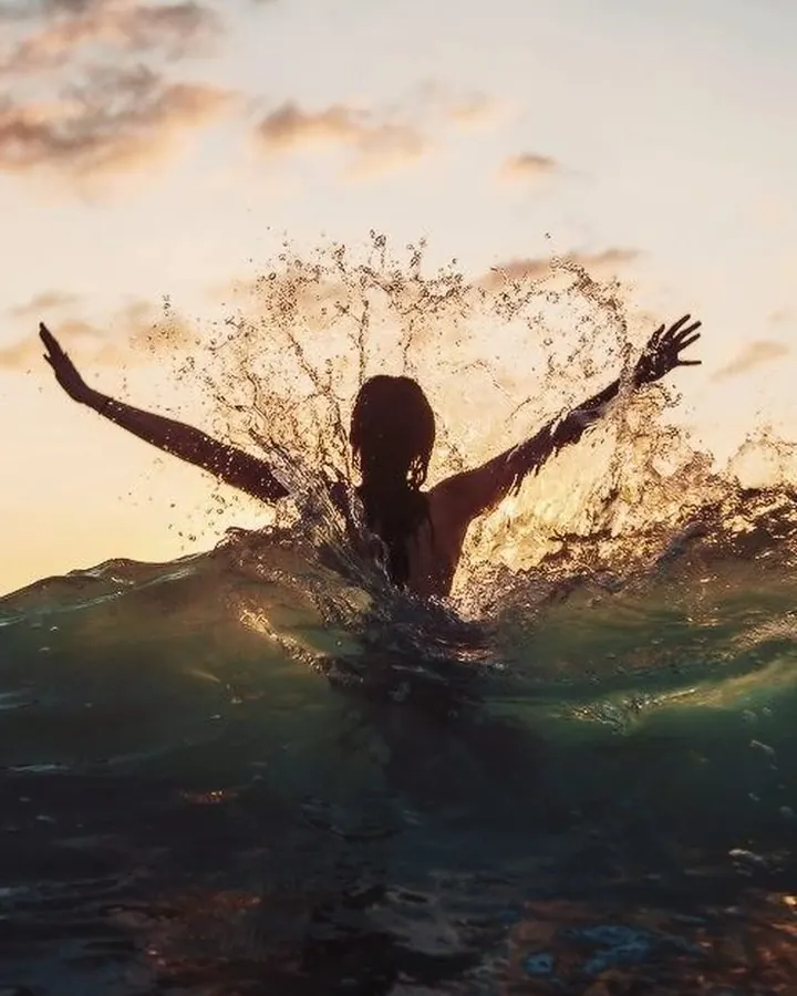 Silhouette féminine de dos dans l’eau au coucher de soleil
