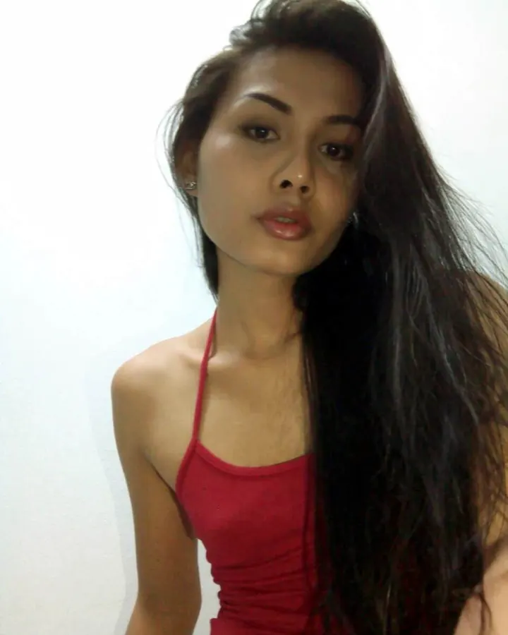 Jeune femme aux cheveux bruns, regard direct, portant un haut rouge, sur fond blanc.
