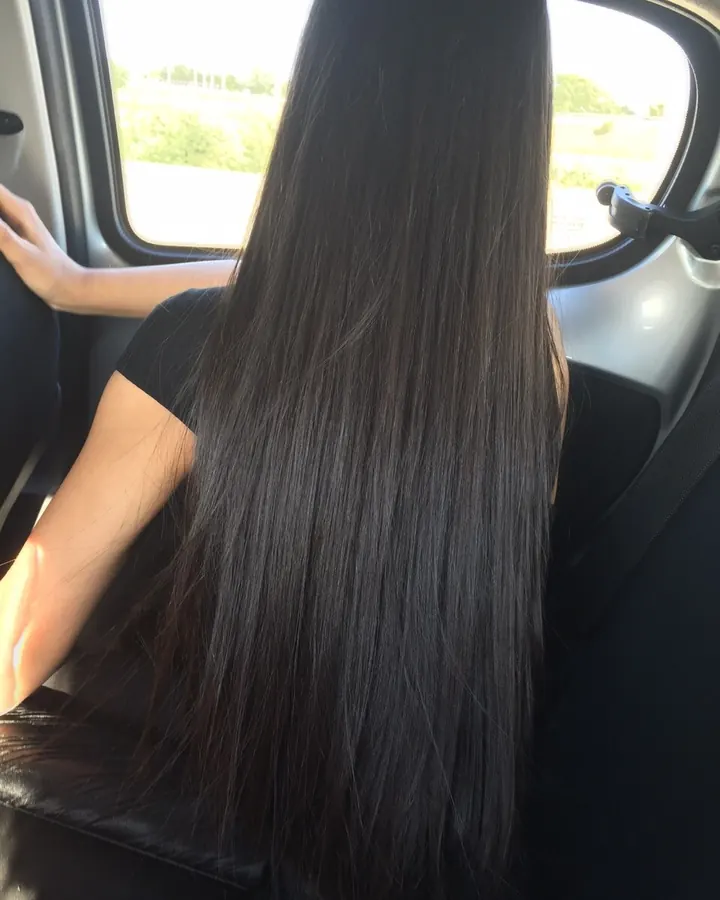 Femme aux cheveux longs prenant un selfie dans un miroir, portant un haut noir et un short noir à bordure blanche, dans une chambre bleue.