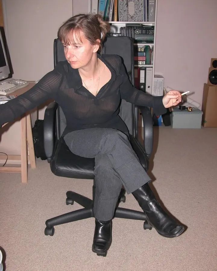 Femme aux cheveux bruns, portant un haut rouge, assise sur un canapé, regardant vers le bas.