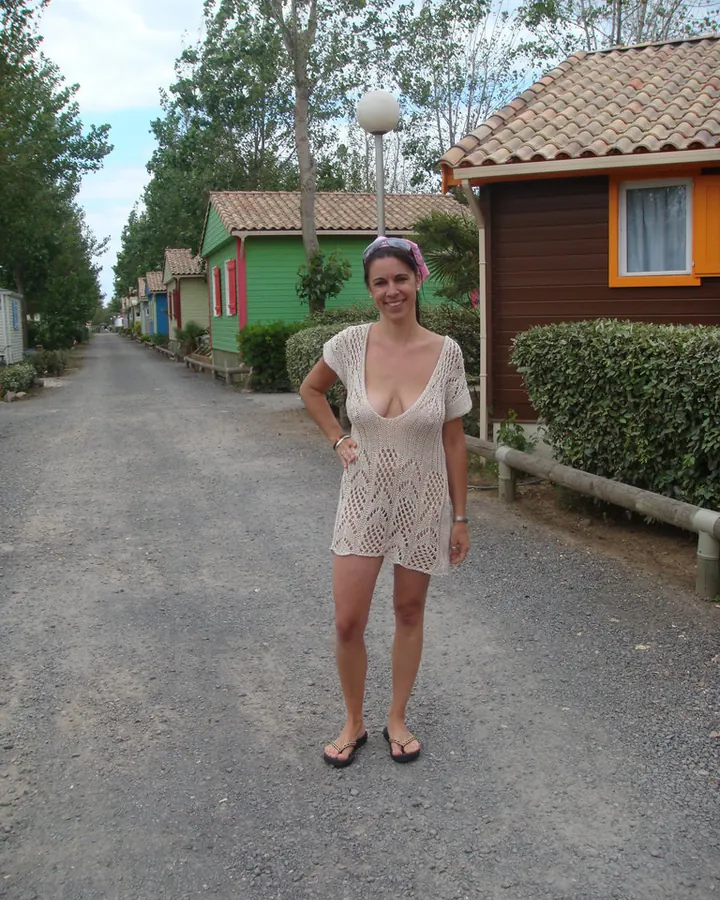 Femme aux cheveux bruns, portant un haut noir, assise sur un canapé, regardant vers le bas.