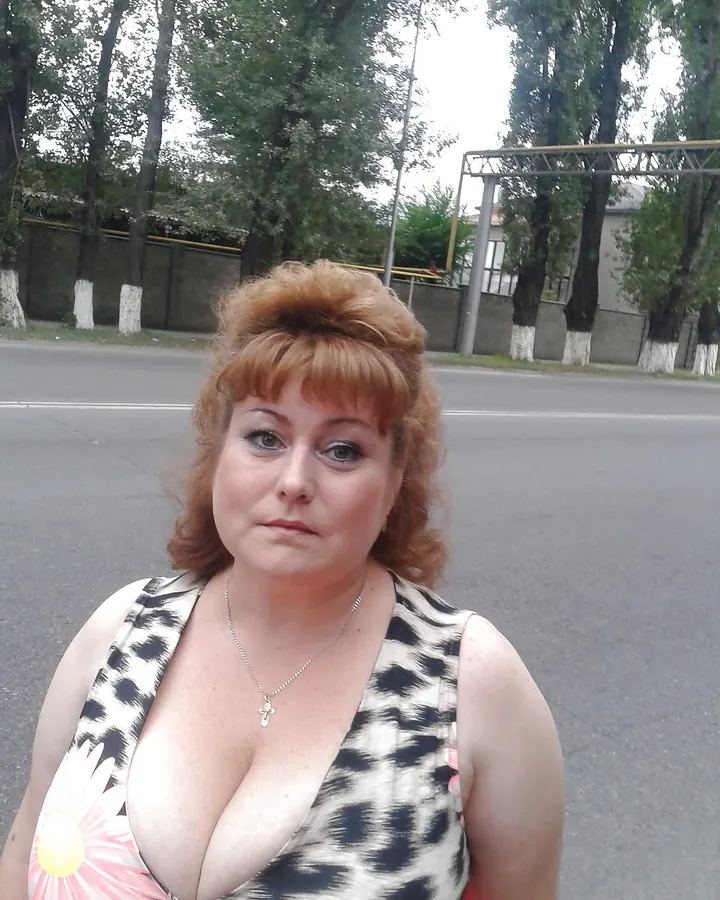 Femme aux cheveux châtains, en robe à imprimé floral, debout sur une route