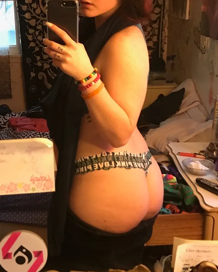 Femme prenant un selfie dans une chambre, en sous-vêtement, avec des bracelets colorés.