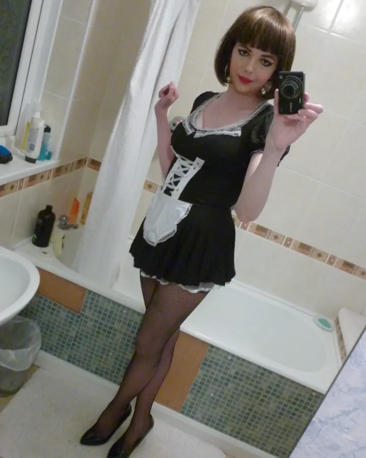 Femme aux cheveux châtains, portant un haut noir et un short en jean, prenant un selfie dans un dressing.