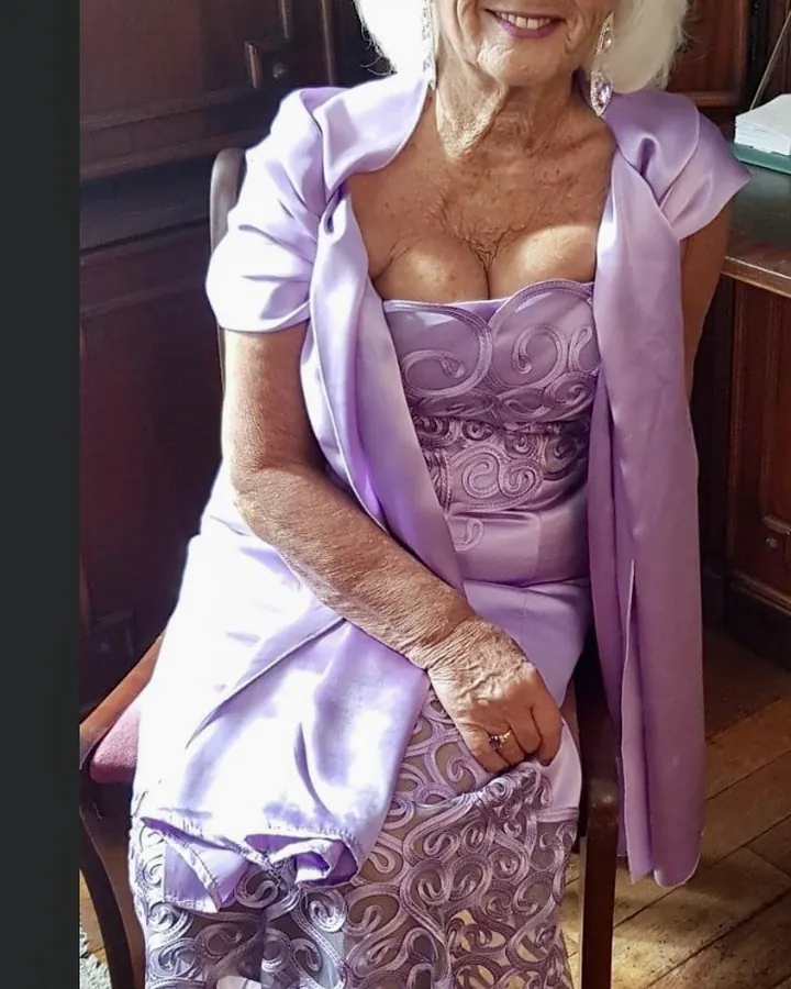 Femme âgée aux cheveux blancs, en robe violette, assise, souriante