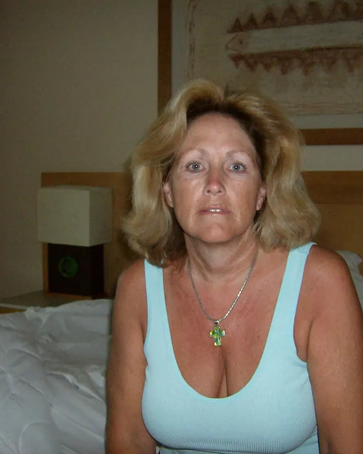 Femme aux cheveux bruns prenant un selfie, vêtue d'un haut noir, regardant l'appareil.