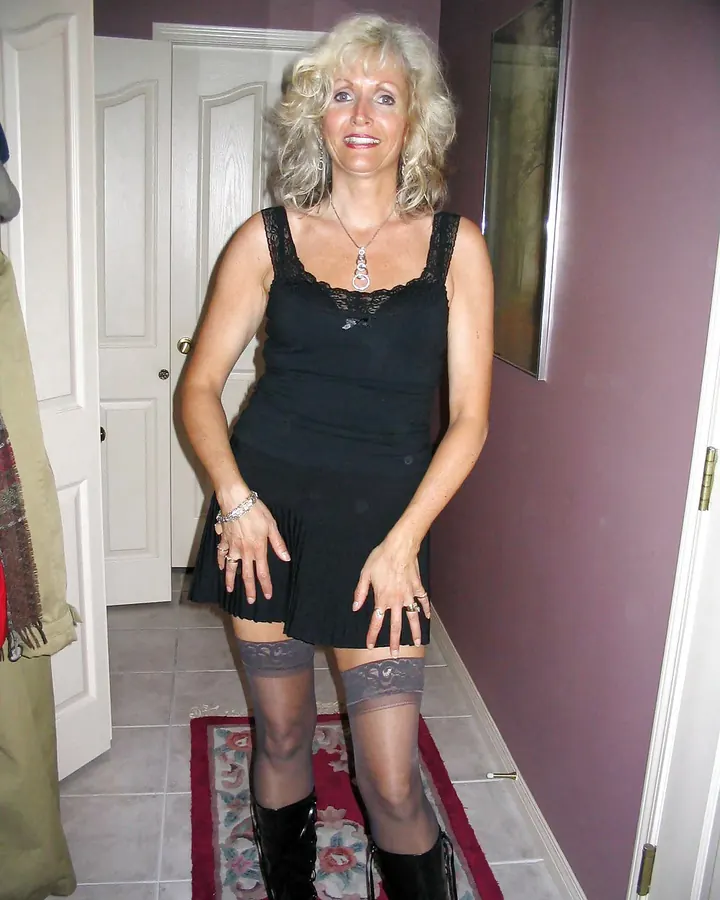 Femme blonde en robe noire courte et bas noirs